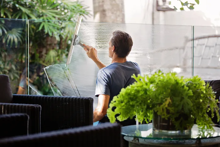 Person cleaning indoor glass windows with a yellow cloth