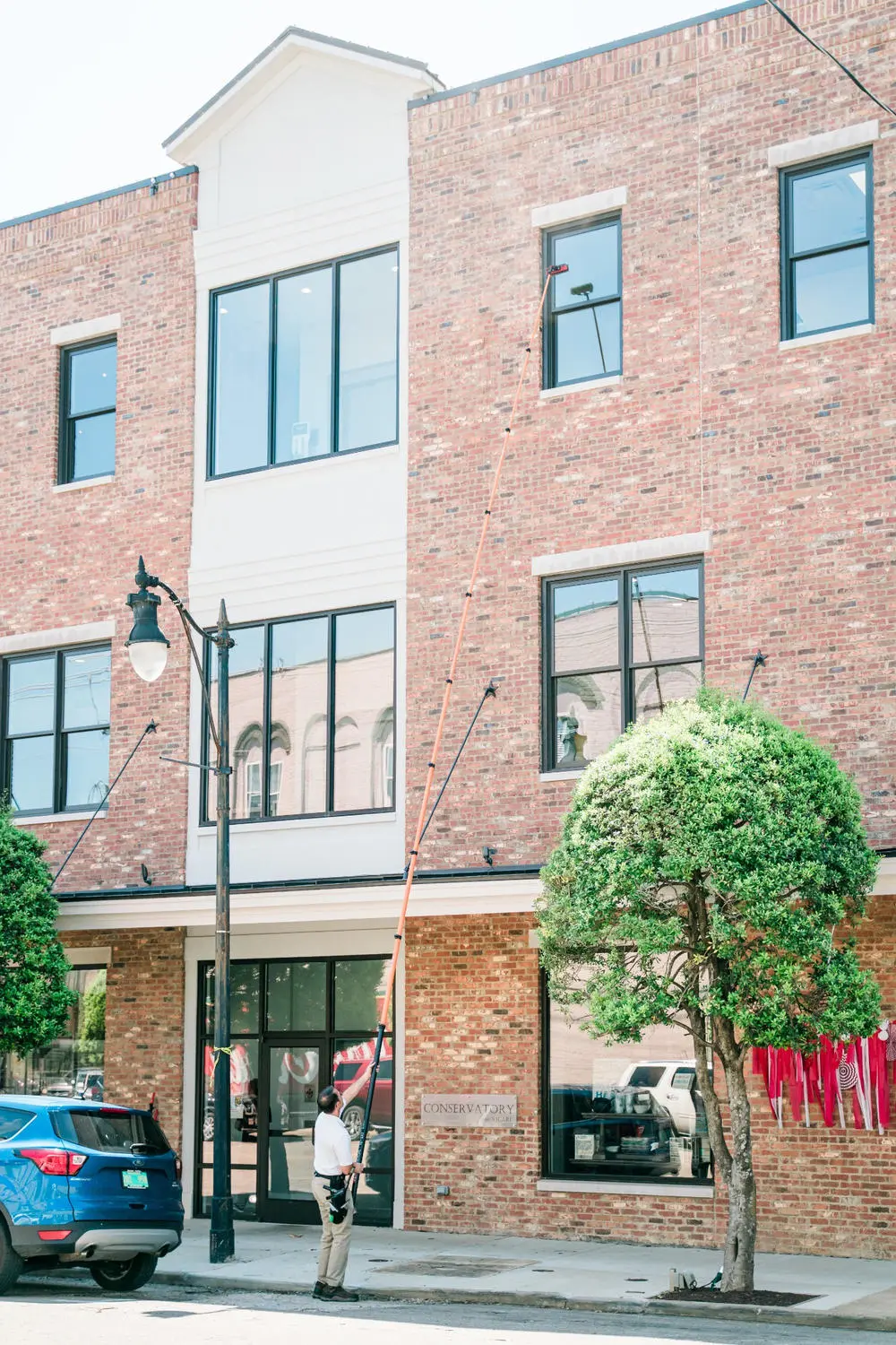 Craig cleaning the upper windows of a multi-story commercial building