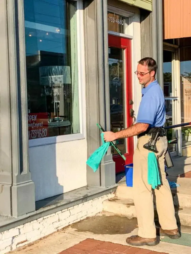 Craig cleaning the exterior window of a local storefront