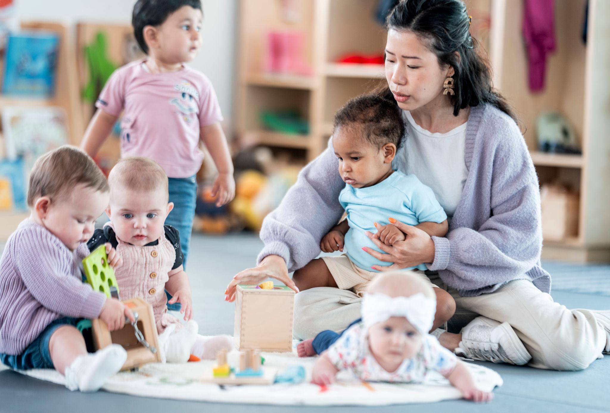 Daycare worker with several children in a warm, lively setting